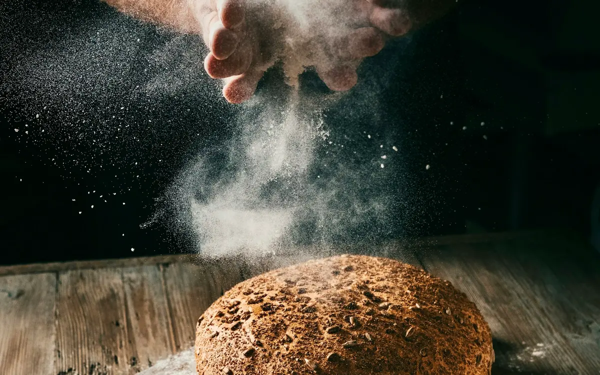 A sourdough loaf being dusted with flour