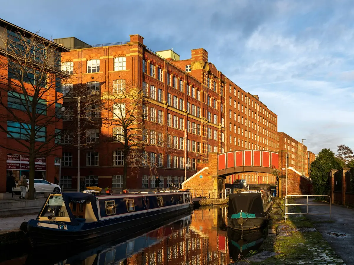 Red-brick mills and narrowboats on the canal in Ancoats at sunset