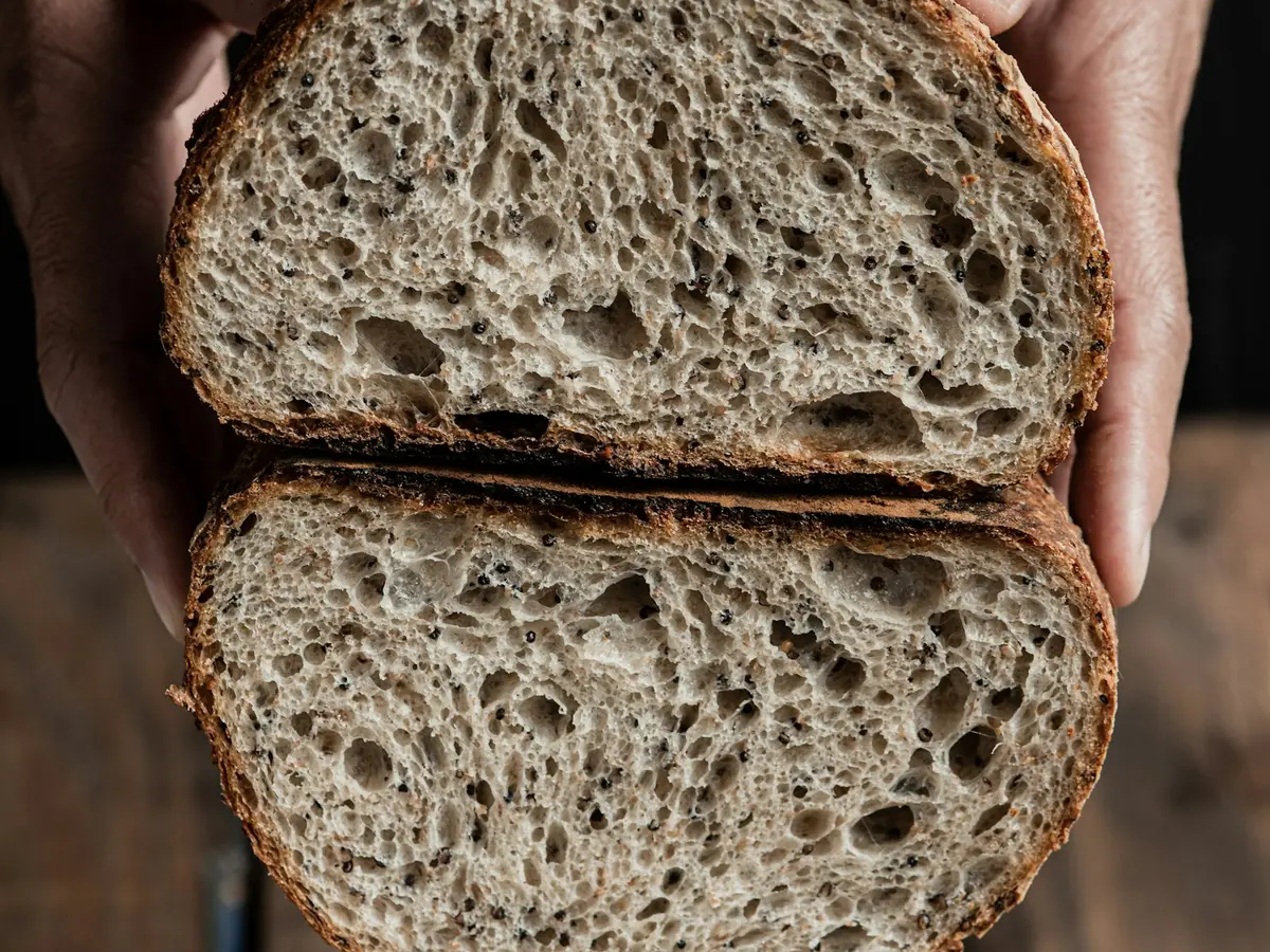 Hands holding a sourdough loaf cut in half