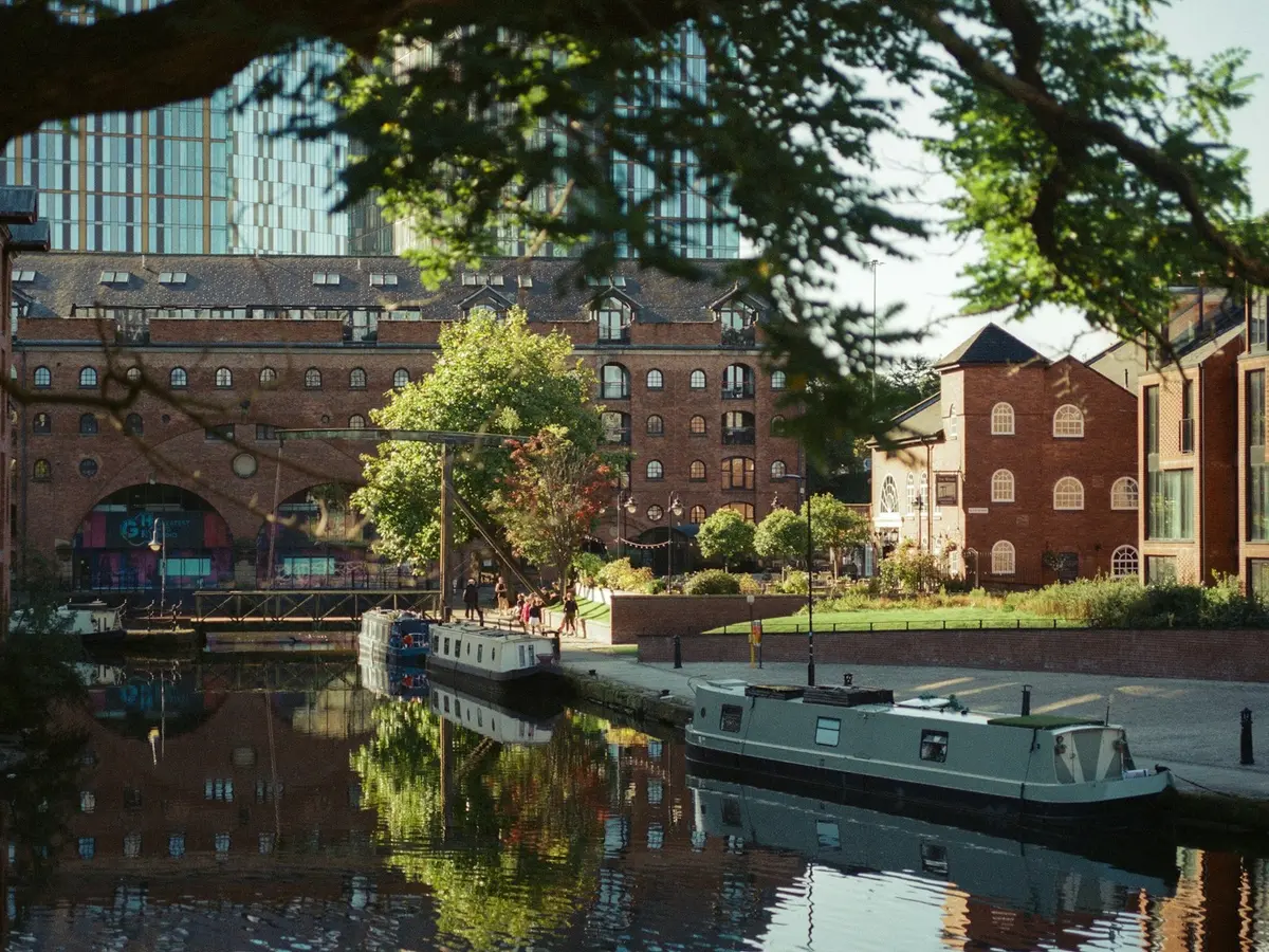 Narrowboats moored on a canal between brick buildings
