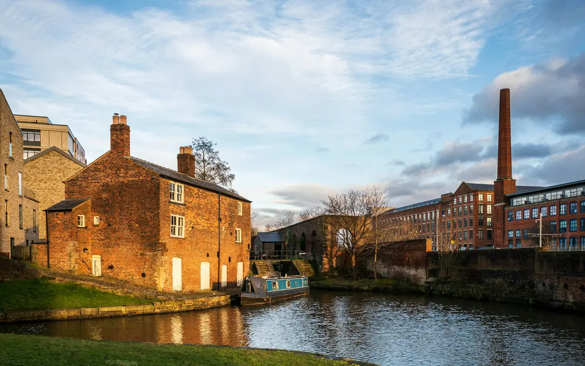 A brick canal-side cottage and a mill chimney in Ancoats